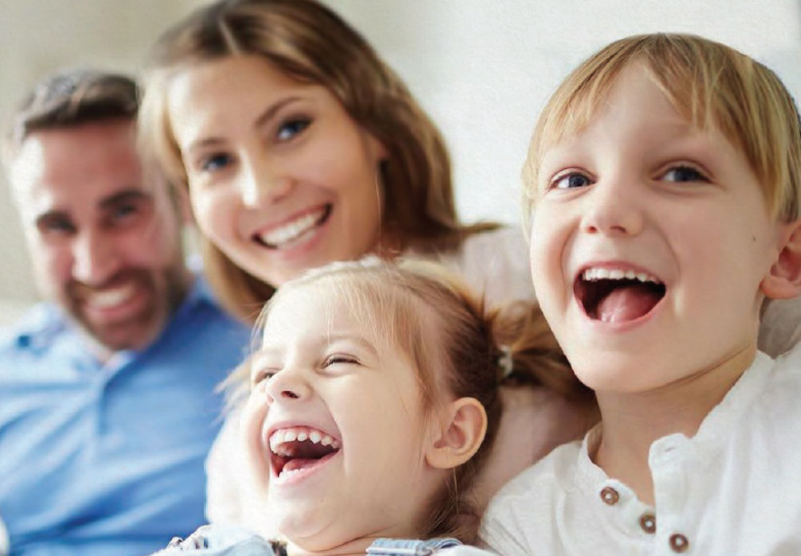 Family of four with young children laughing.