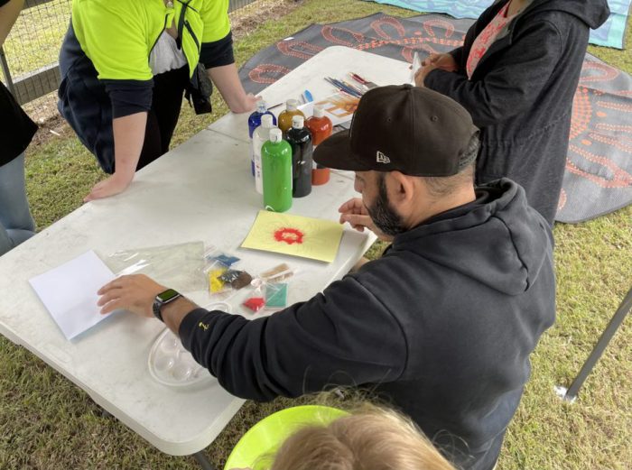 Ben sitting at a table doing Aboriginal art with youth while connecting young people to culture