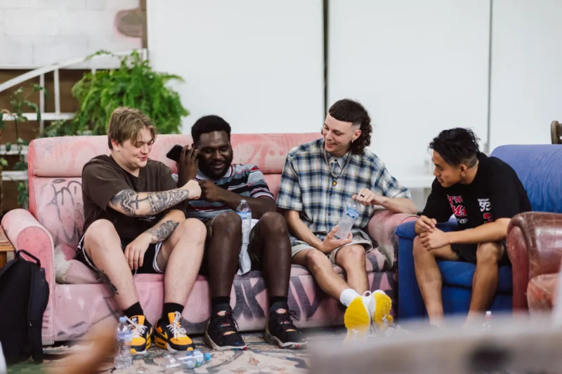 Group of four young men sitting on a couch having a fun conversation.