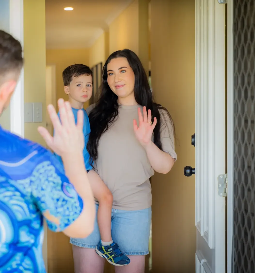 Anglicare children. youth and family worker waving to parent and child.