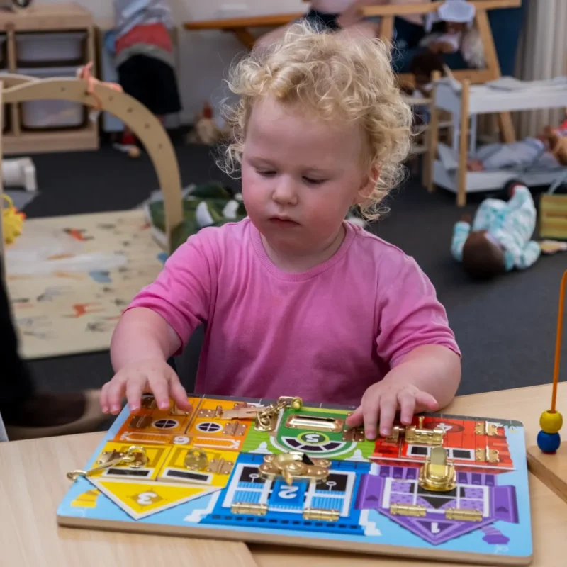 Child playing with a busy board at Operation Kinder Community, Children and Parenting Program.