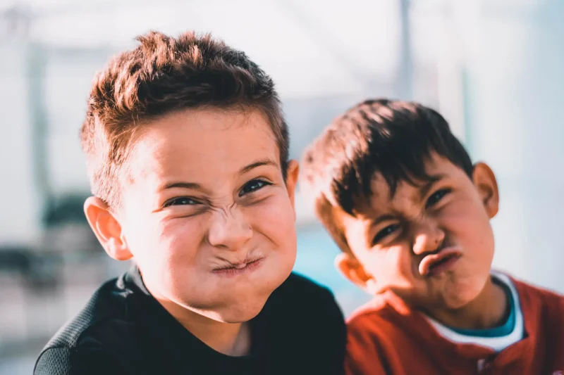 Two young boys pulling faces in a playgroup.