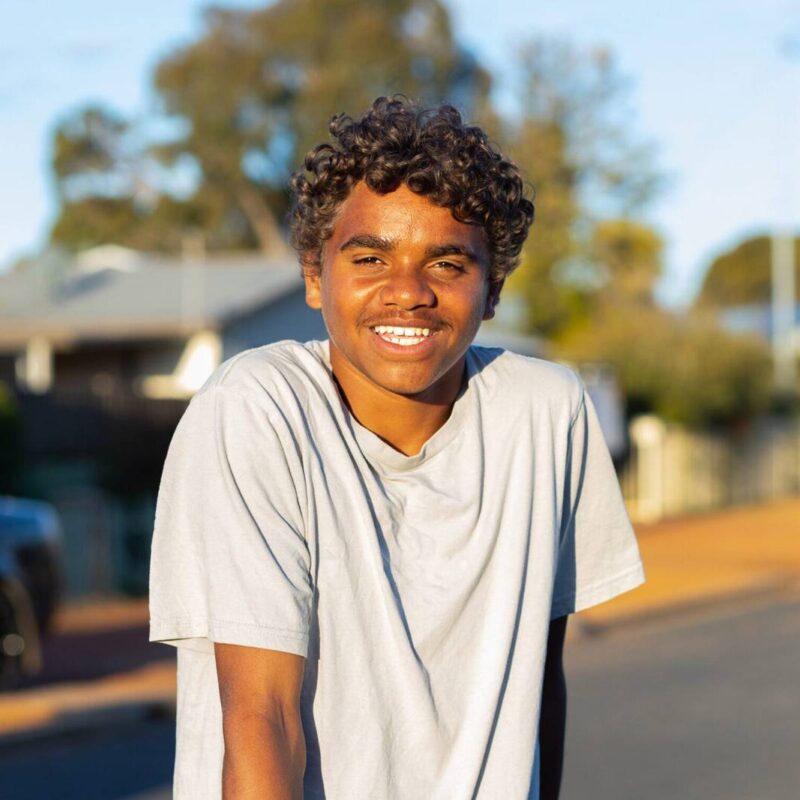 First Nations Foster Care child standing in their front yard and smiling.