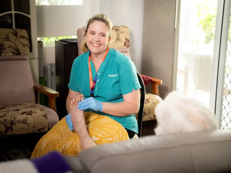 allied health worker supporting elderly client with podiatry massage