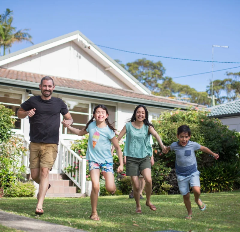 Brisbane family holding hands and running in front yard.