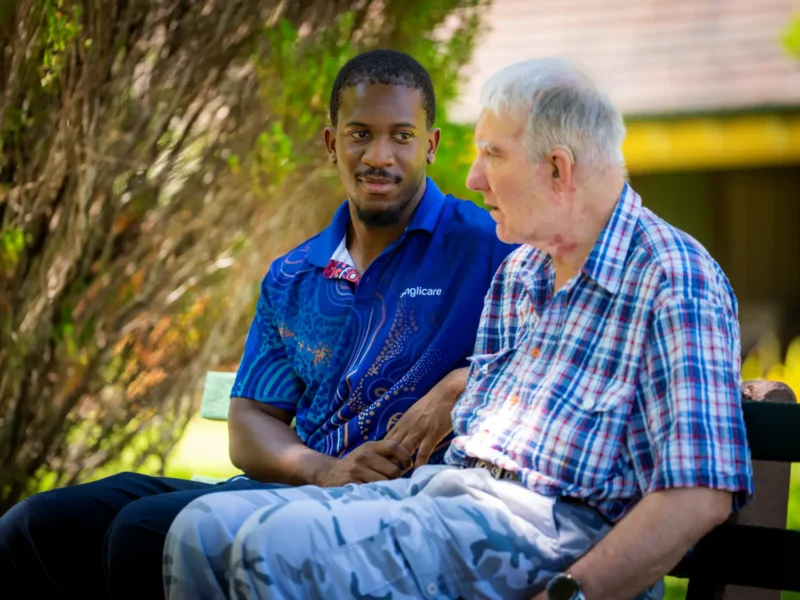 Anglicare worker siting with elderly male in residential respite care