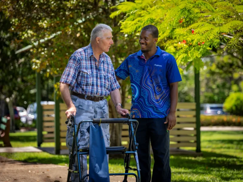 Aged care resident walking with Anglicare worker