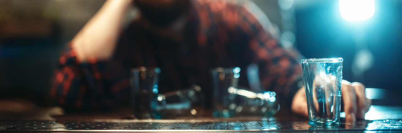 Alcohol Awareness: Person sitting at a bar with an empty shot glass in front of them