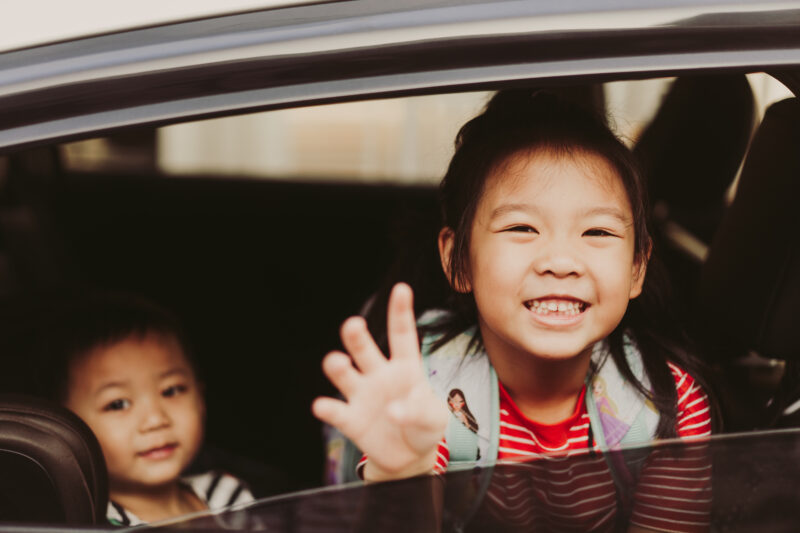 Two young children sitting in backseat of car after being placed in emergency foster care.