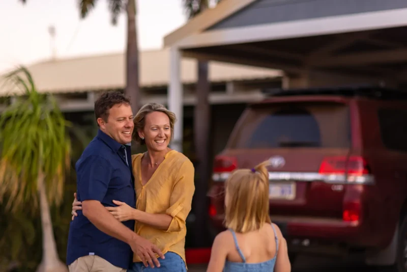 Foster care family standing outside of their house with a mother, father and young girl.