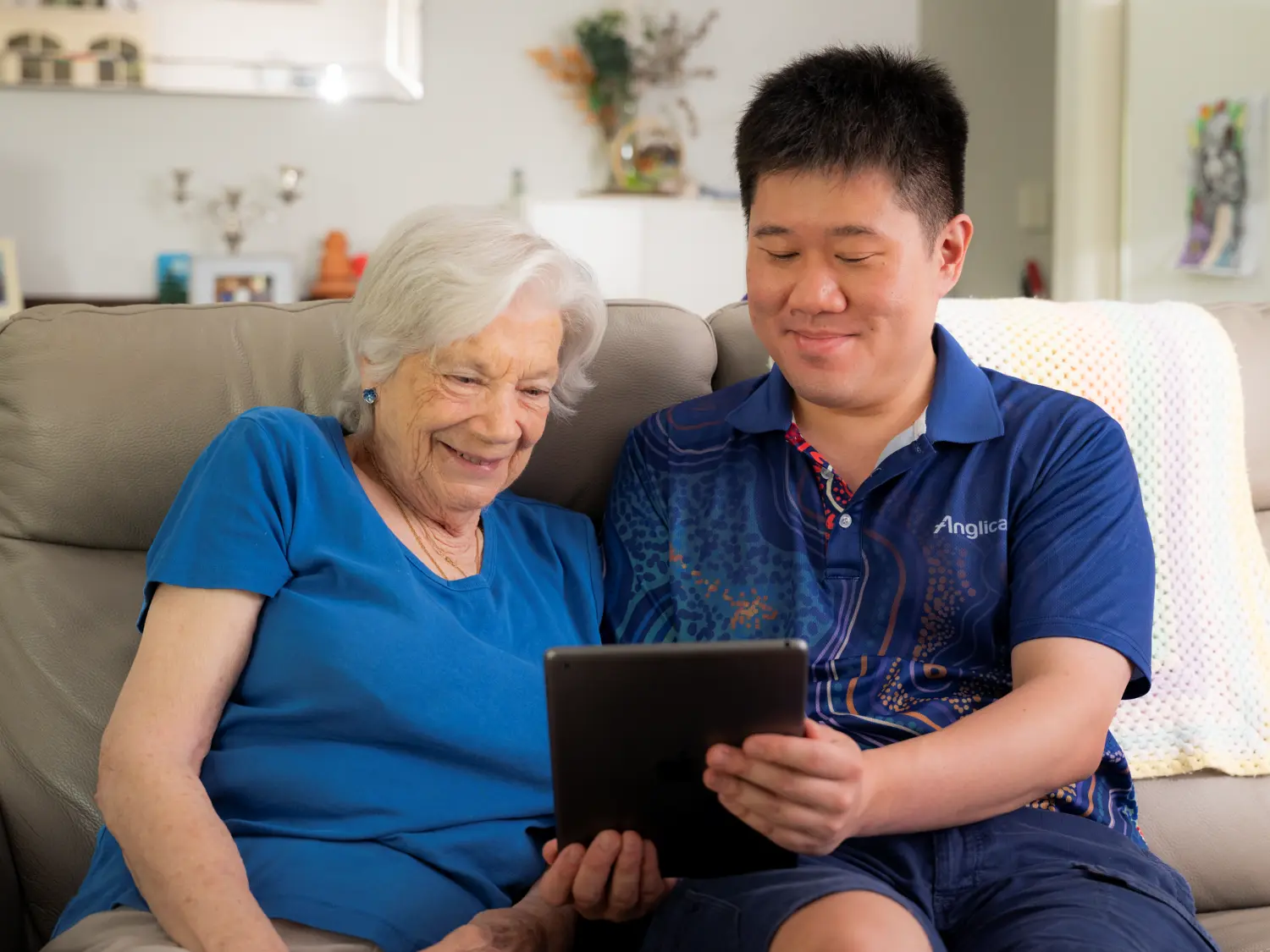 Anglicare Home Care Worker showing elderly female client information on Tablet