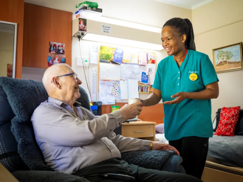 Residential aged care nurse giving medicine to elderly male resident