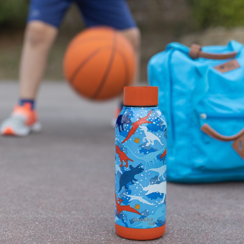 Child playing with a basketball with school bag and drink bottle in shot