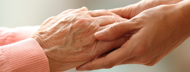 Carer compassionately holding loved ones hand