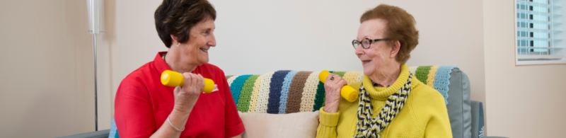 Physio and client lifting weights while sitting down