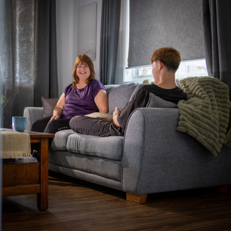 Youth worker sitting on a couch with young person in a residential home