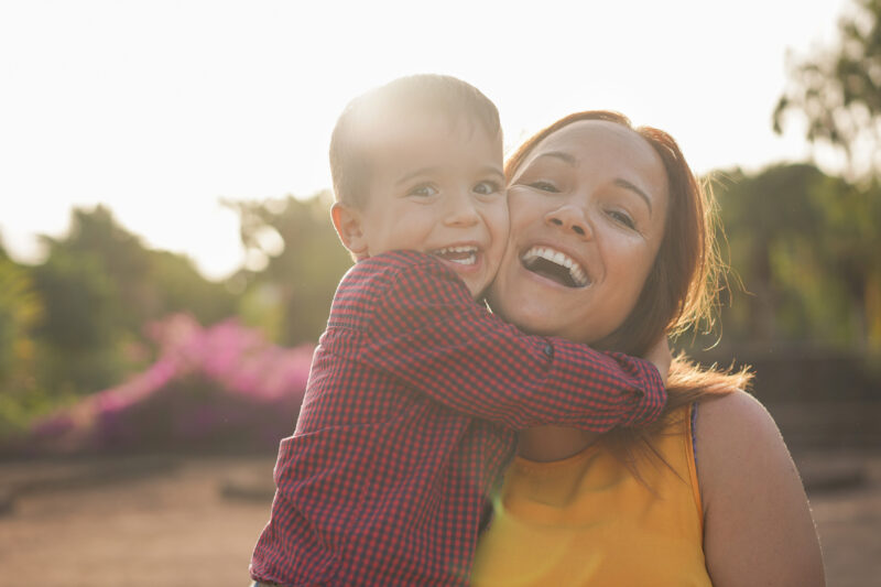 Mother and young son holding each other and smiling to camera