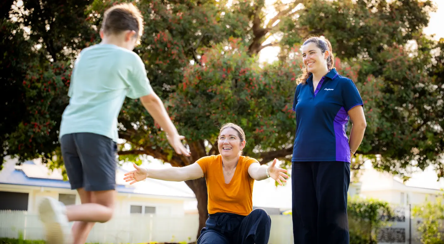 Foster carer about to hug child, whilst Anglicare worker provides support