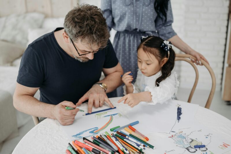 Foster carer and young child drawing together at a table, illustrating the supportive, nurturing relationships foster care services aim to provide